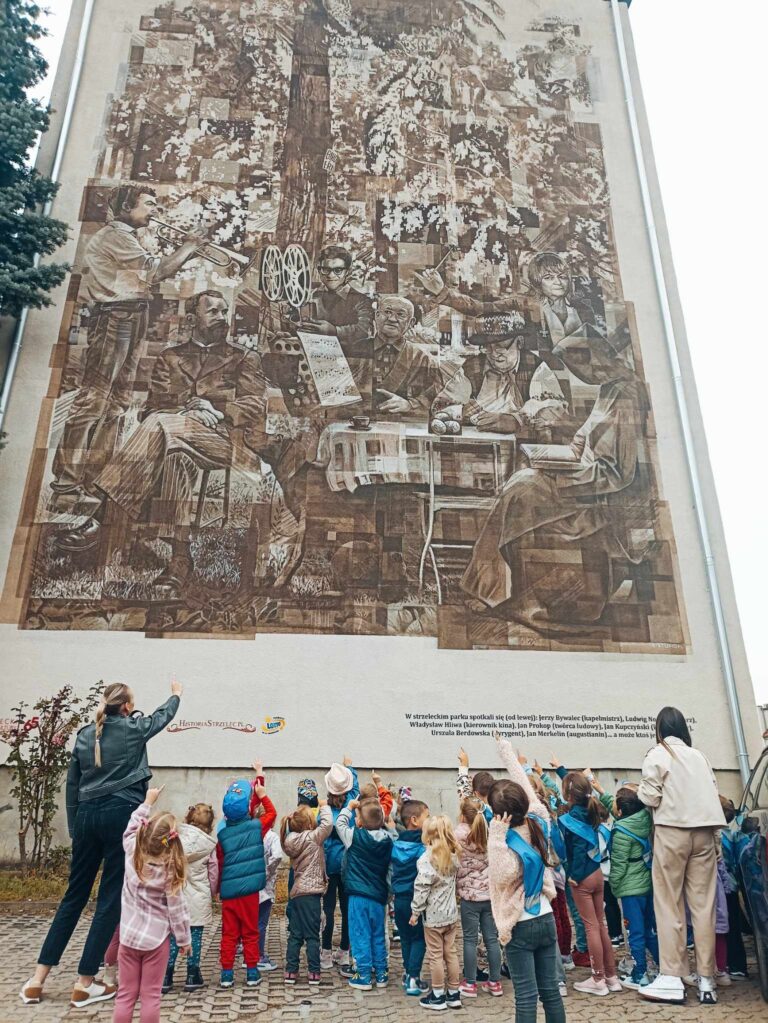 Na zdjęciu dzieci oglądają mural