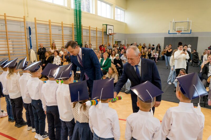 Na zdjęciu burmistrz pasująca dzieci na uczniów szkoły.