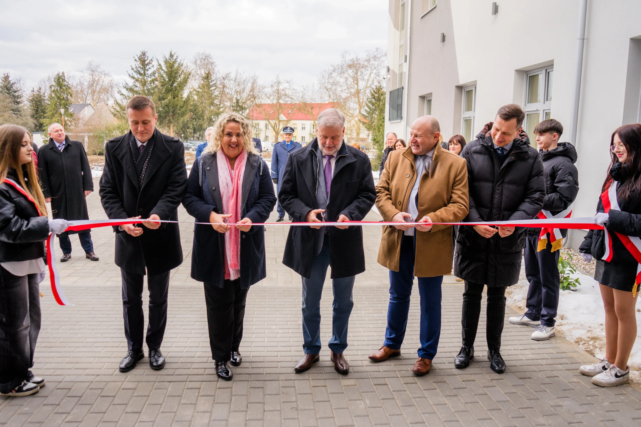 Zdjęcie przedstawia różne osoby przecinające wstęgę.