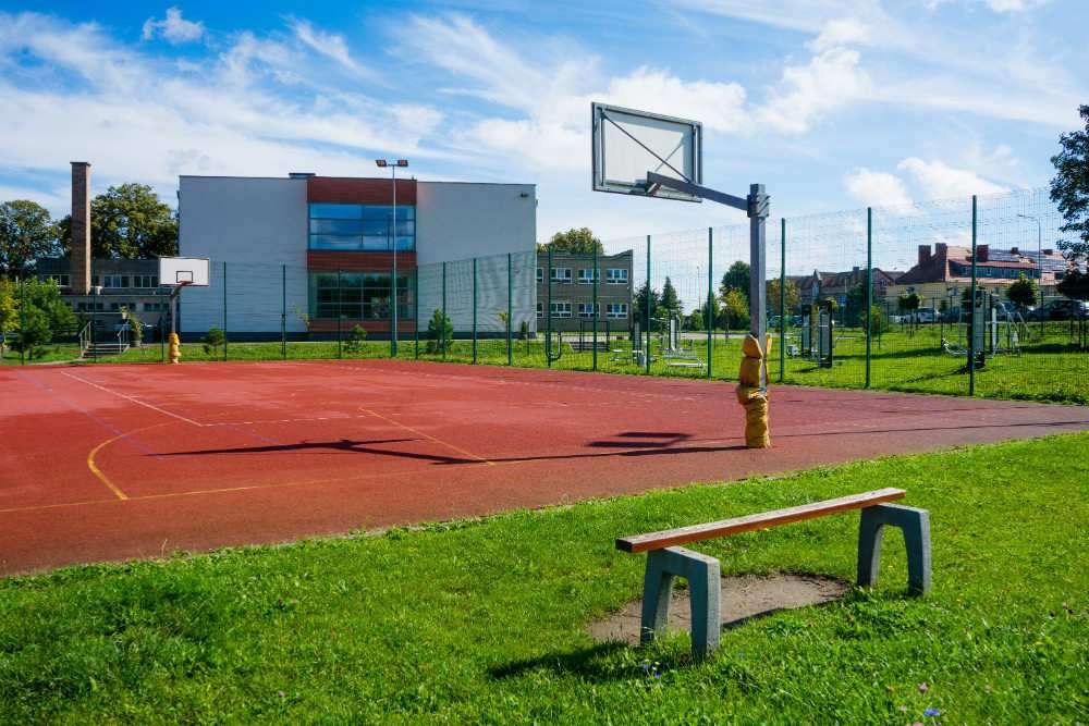 Na zdjęciu widoczne jest boisko do koszykówki, w tle szkoła.